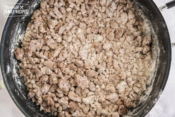 Sausage coated in flour in skillet to make a sausage gravy for biscuits and gravy