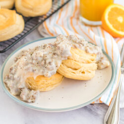 Two biscuits on a plate topped with sausage gravy