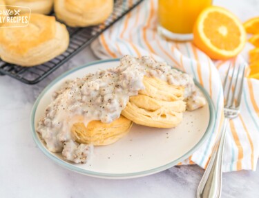 Two biscuits on a plate topped with sausage gravy