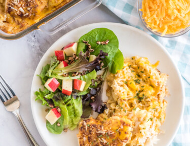 Chicken and Rice Casserole on a plate with some salad and the casserole dish in the background