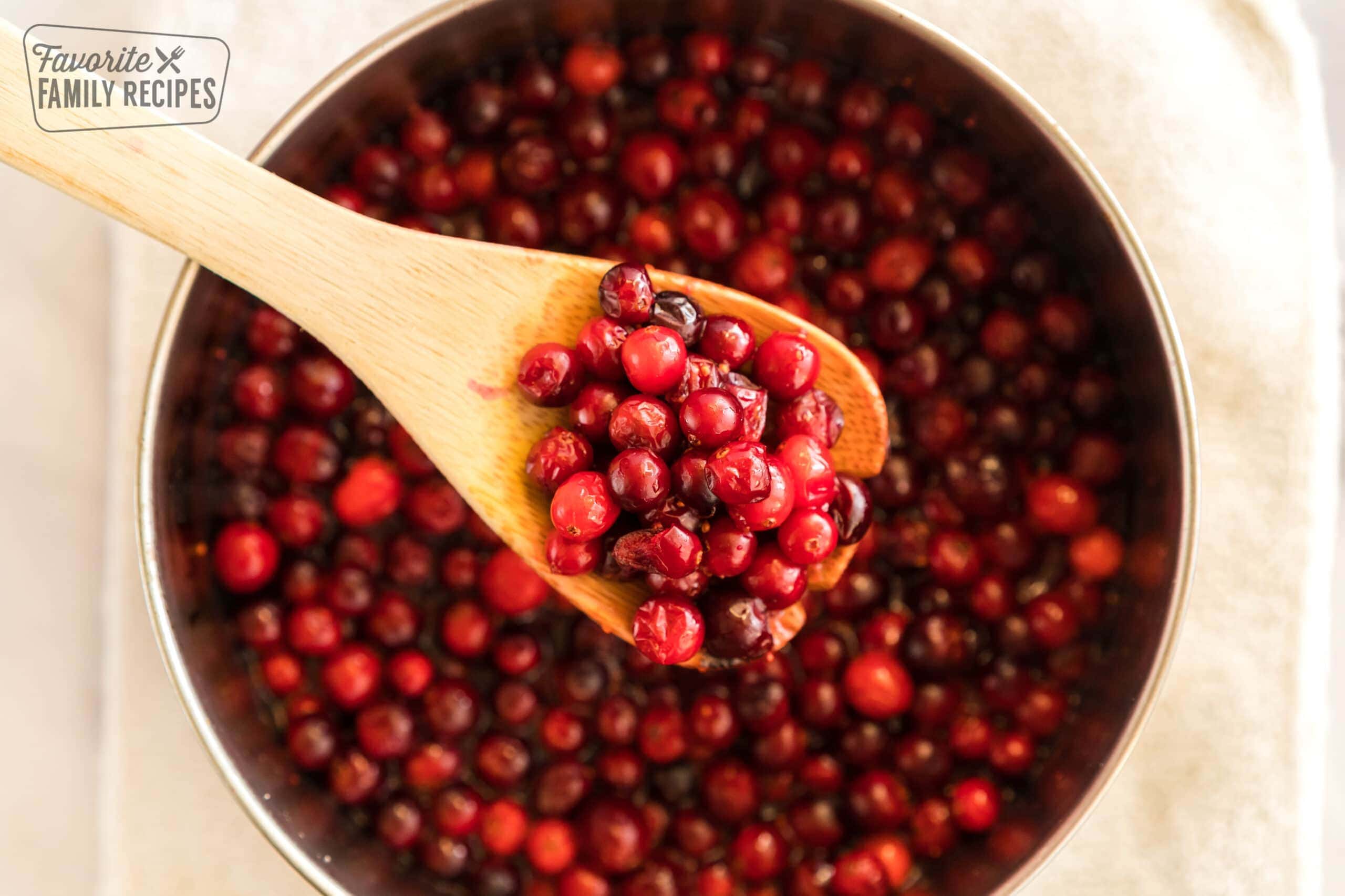 Fresh cranberries cooking in a saucepan to make cranberry orange sauce