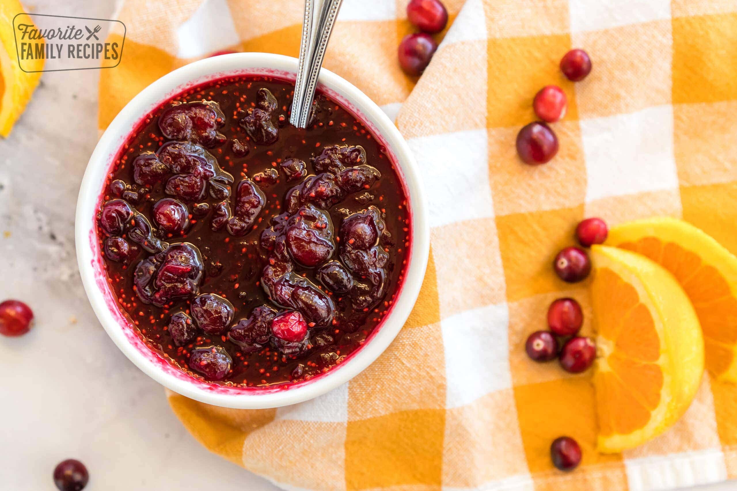 Cranberry orange sauce in a dish with fresh cranberries sprinkled on the side