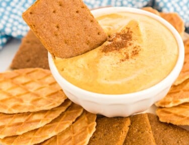 a graham cracker being dipped in pumpkin dip