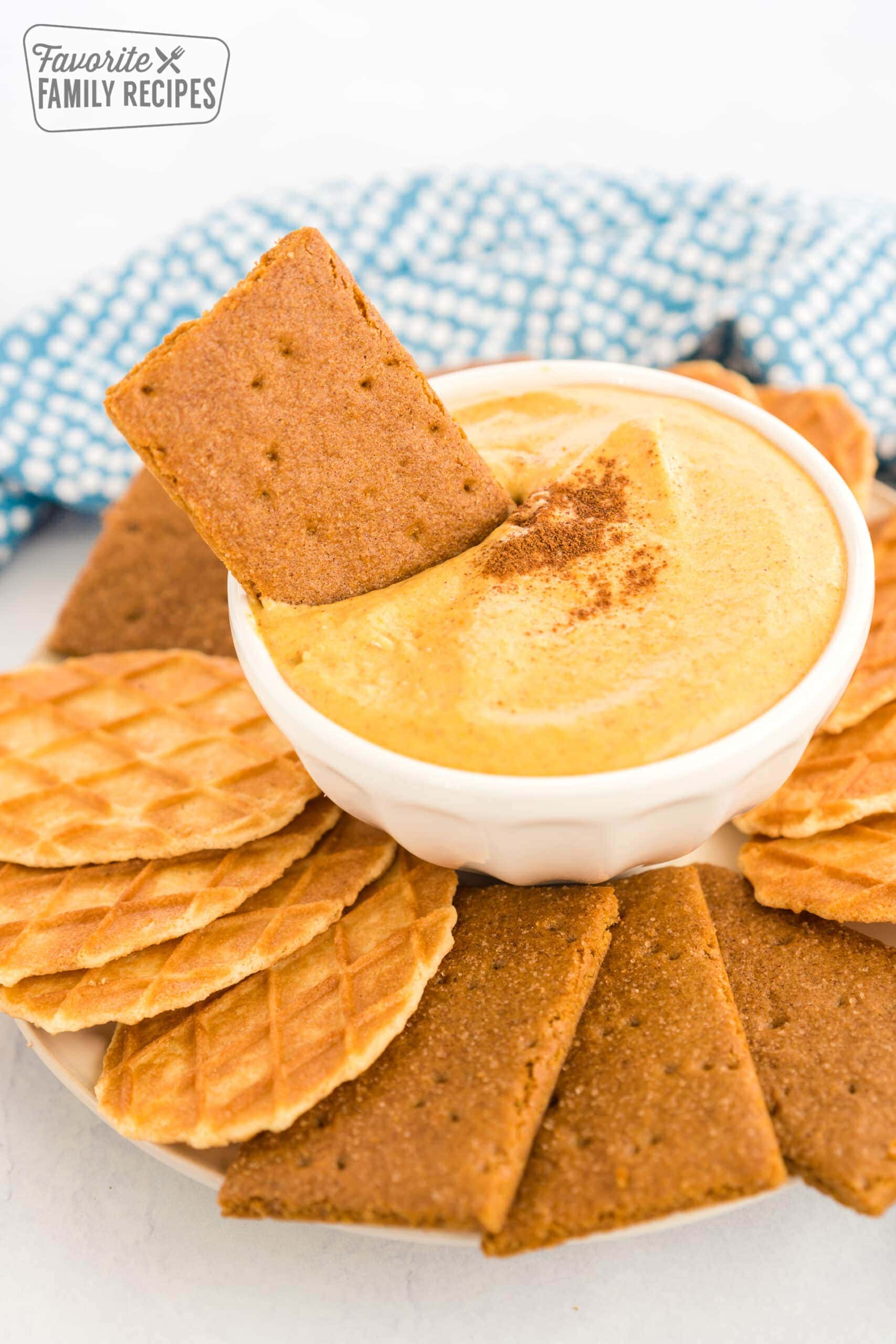 A graham cracker being dipped in pumpkin dip.