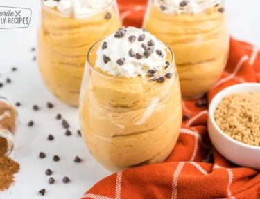 Pumpkin mousse cups topped with whipped cream and chocolate chips on top