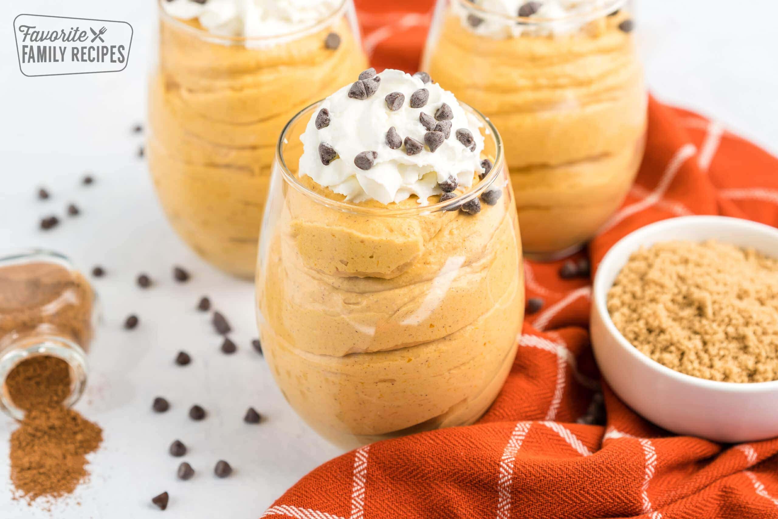 Pumpkin mousse cups topped with whipped cream and chocolate chips on top.