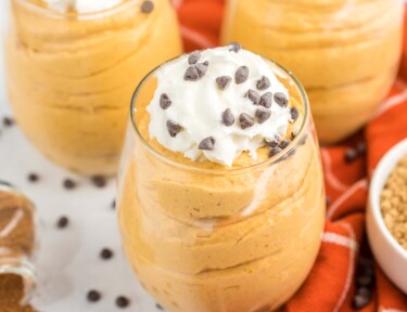 Three cups of pumpkin mousse topped with whipped cream and chocolate chips
