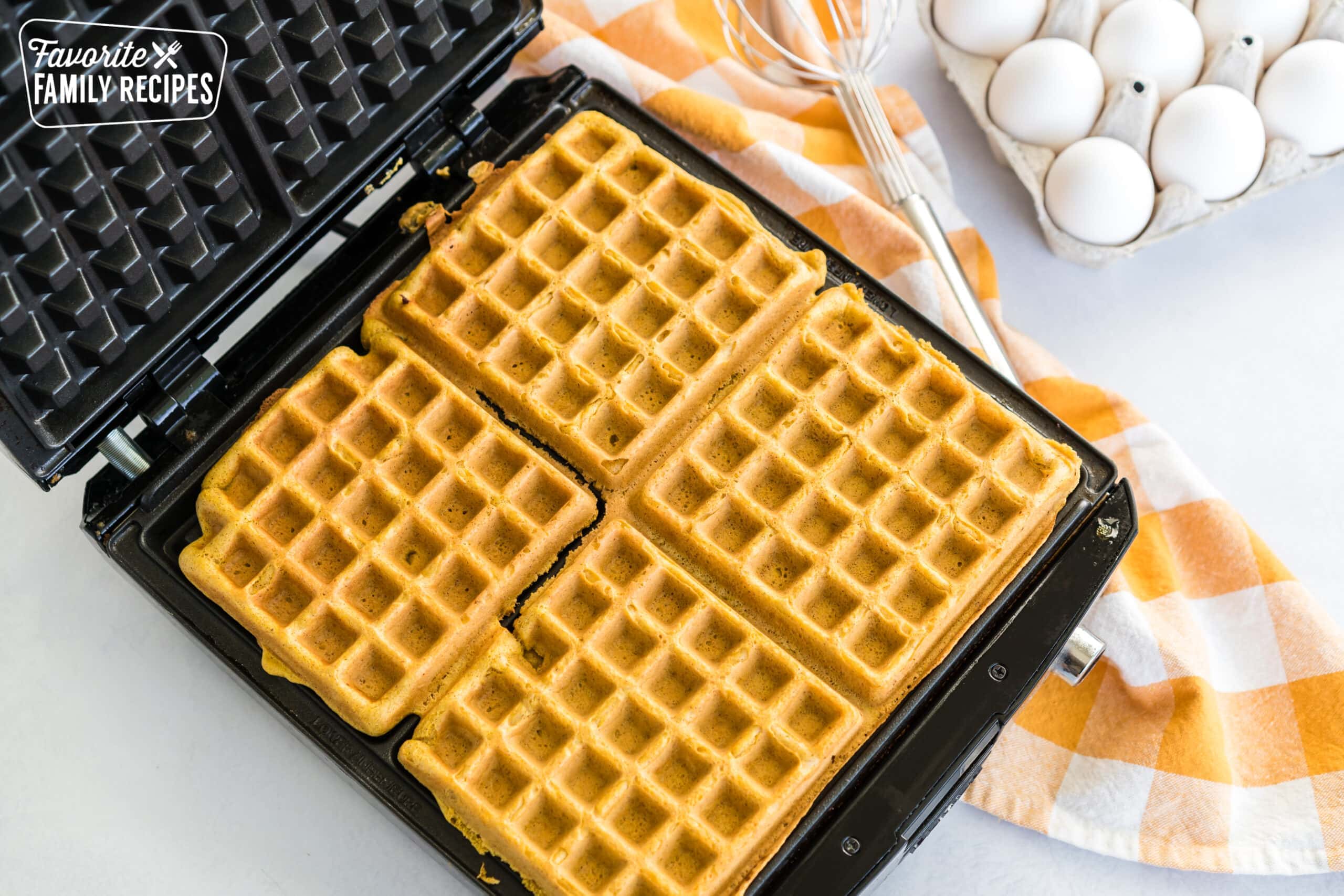 Pumpkin waffles cooking in a waffle iron.