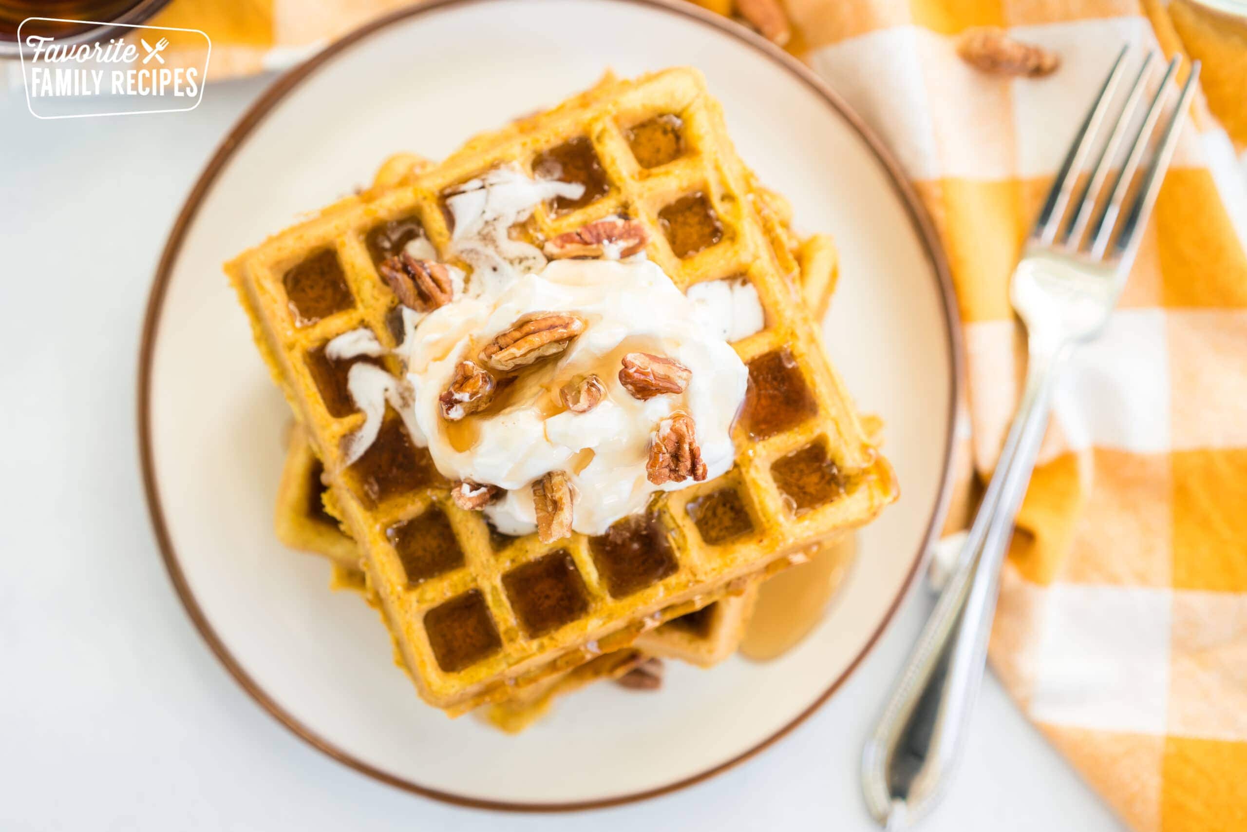 Pumpkin waffles with maple syrup drizzling down them.