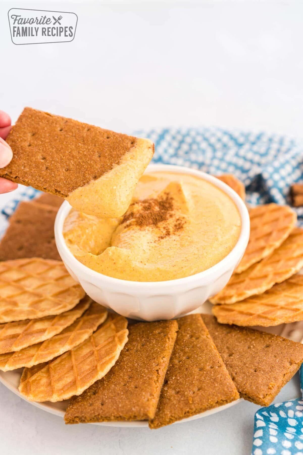 A graham cracker section dipped in a bowl of pumpkin dip