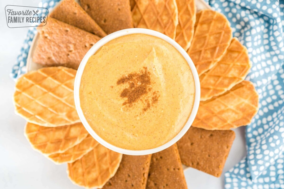Pumpkin dip in a white bowl surrounded by graham crackers and butter waffle cookies