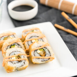 shrimp tempura rolls on a plate with soy sauce and chopsticks