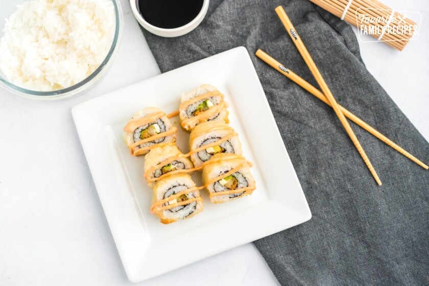 Shrimp tempura godzilla roll on a plate with chopsticks