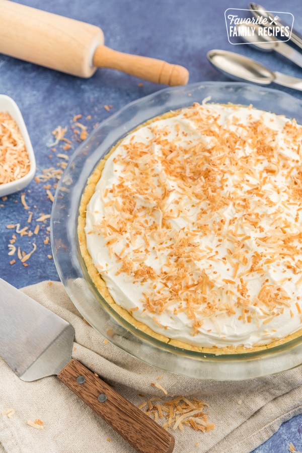 A coconut cream pie with a rolling pin on the side.