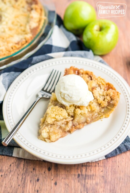 dutch apple pie on a plate with a fork and a scoop of ice cream on top