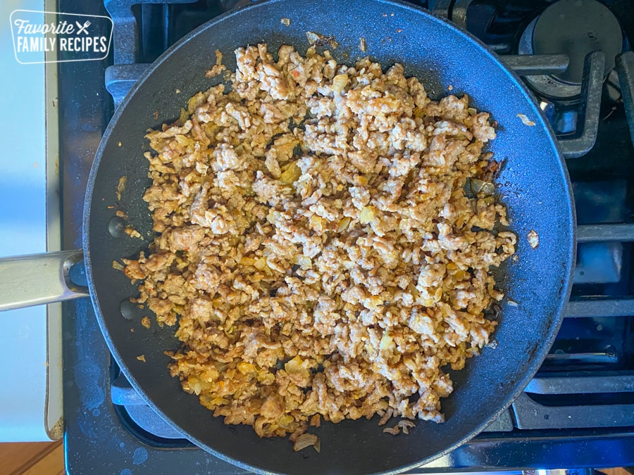 Italian sausage, onions, and garlic sautéing in a skillet