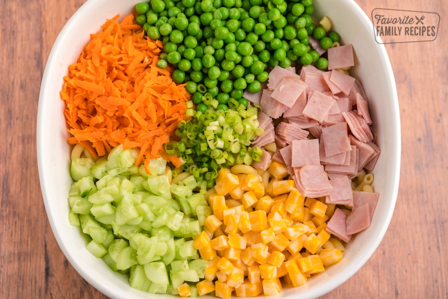 Ham, cheese, carrots, cucumbers, peas, and green onions all diced up in a white bowl