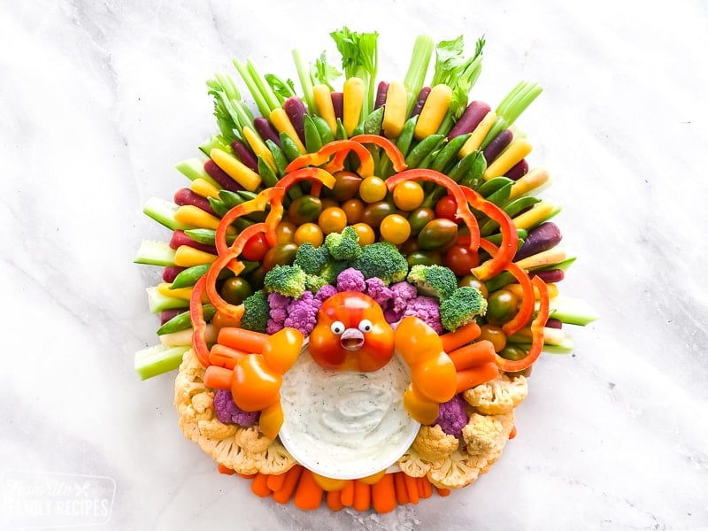 These festive and easy Thanksgiving appetizers are sure to be a hit for your next Thanksgiving feast! Including this adorable turkey shaped veggie tray that is sure to steal the show. A veggie tray made out of vegetables.