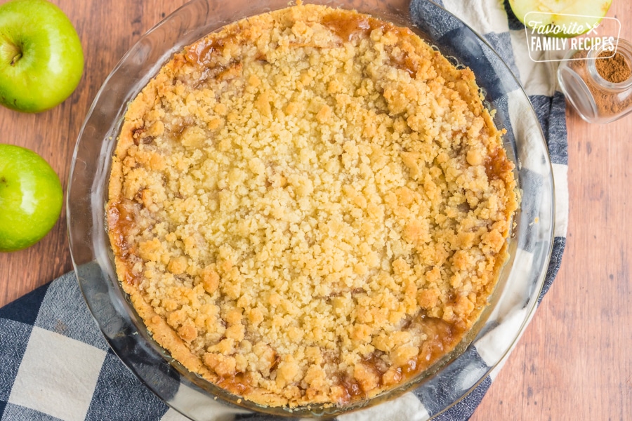 Whole Dutch apple pie with green apples on the side.