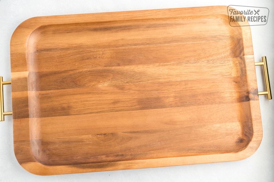 A wooden tray with gold handles