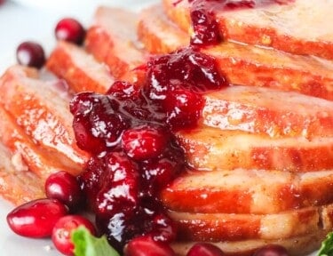 Close up of Christmas ham with cranberry sauce spooned over the top