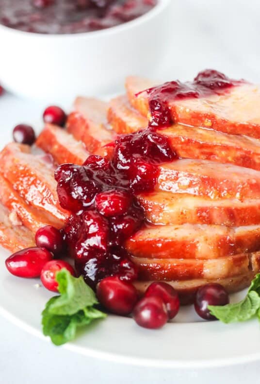 Close up of Christmas ham with cranberry sauce spooned over the top