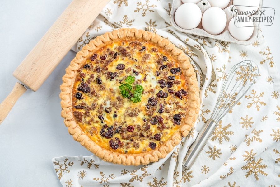 A Christmas Breakfast Quiche on the counter with a rolling pin, whisk, and egg carton.