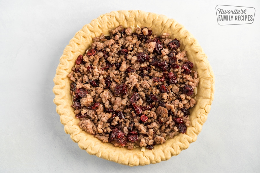 A pie crust filled with cheese, sausage, and cranberries