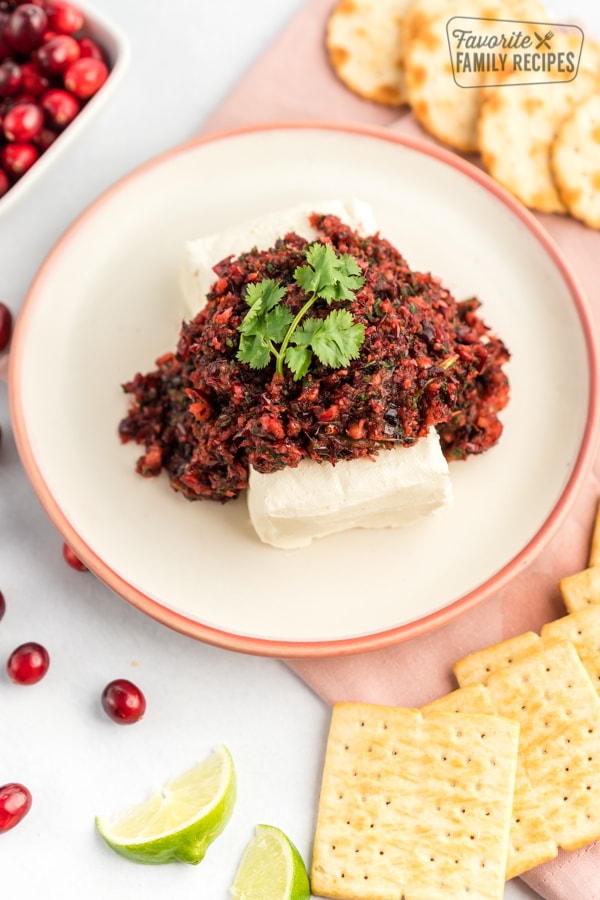 Cranberry salsa over top cream cheese on a white plate. 