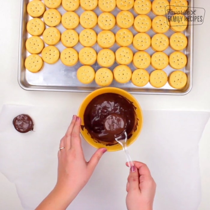 Dipping ritz cookies in melted chocolate