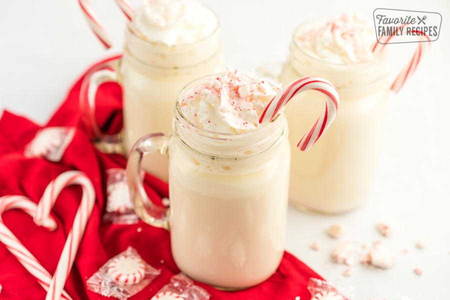 Three mugs of peppermint hot chocolate with whipped cream and candy canes