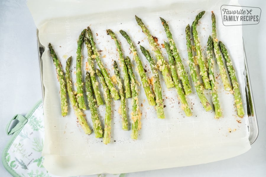Oven Roasted Asparagus is a flavorful side dish for any meal. Topped with olive oil, garlic and cheese, they come out perfectly tender and crisp every time! Roasted Asparagus on a baking sheet, topped with parmesan cheese and seasoning.