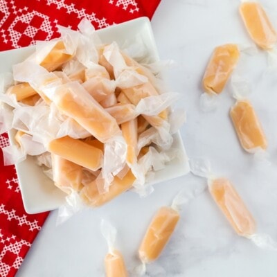 A white dish filled with homemade caramels on Christmas placemat