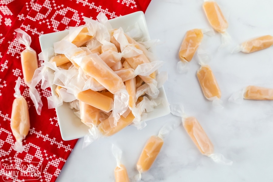 A white dish filled with homemade caramels on a Christmas placemat.