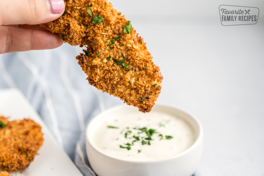 One chicken tender about to be dipped in ranch.