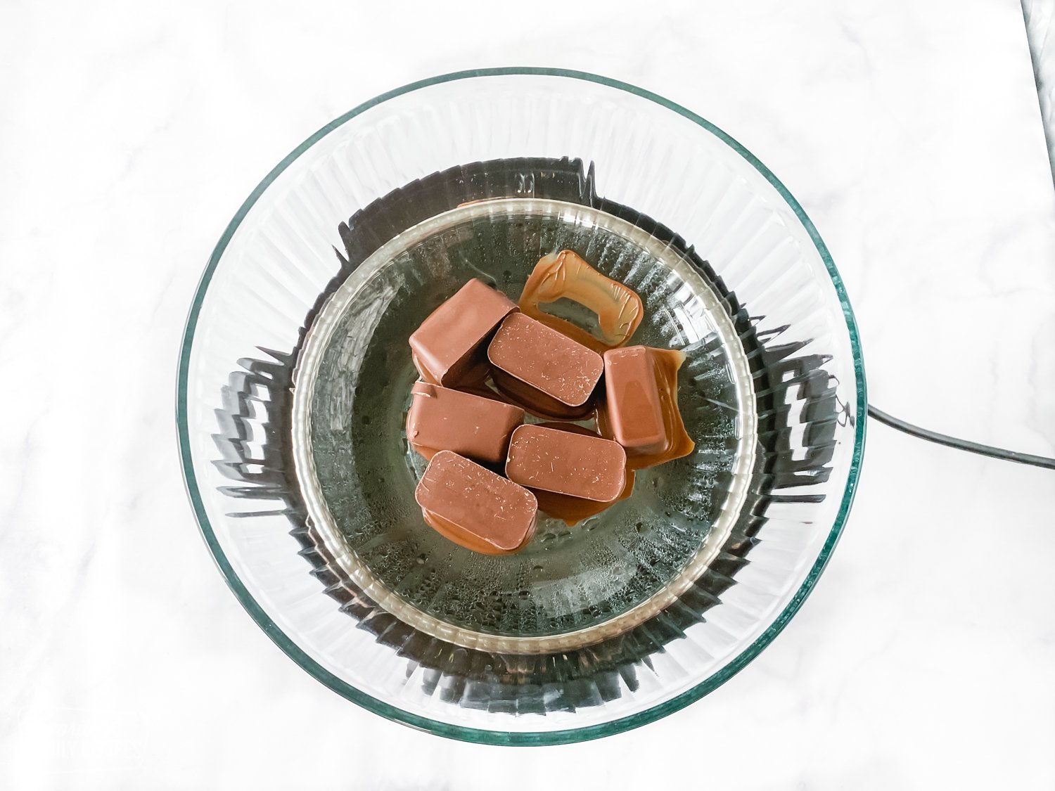 Chocolate being melted in a glass bowl with a boiler.