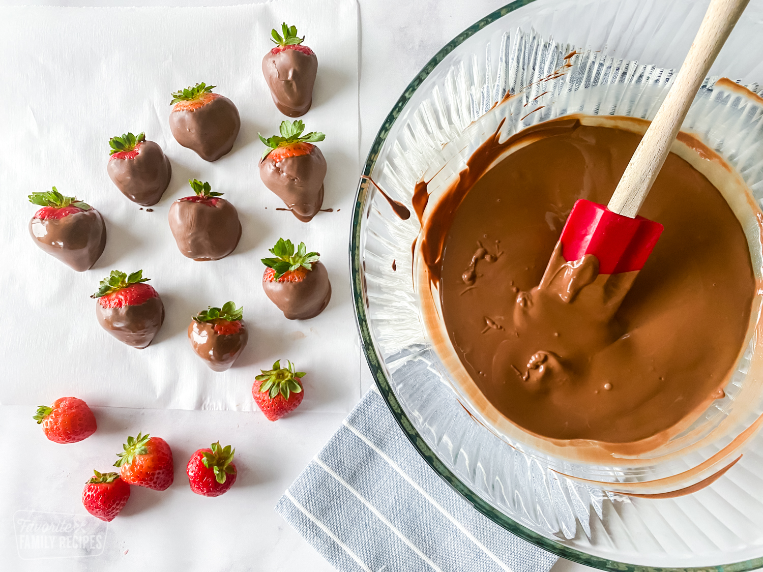 Strawberries dipped in chocolate on parchment paper.