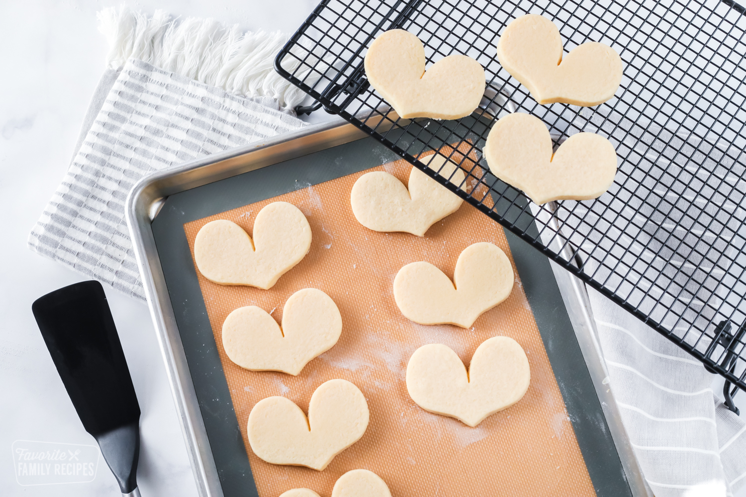 Baked sugar cookies on a baking sheet and cooling rack