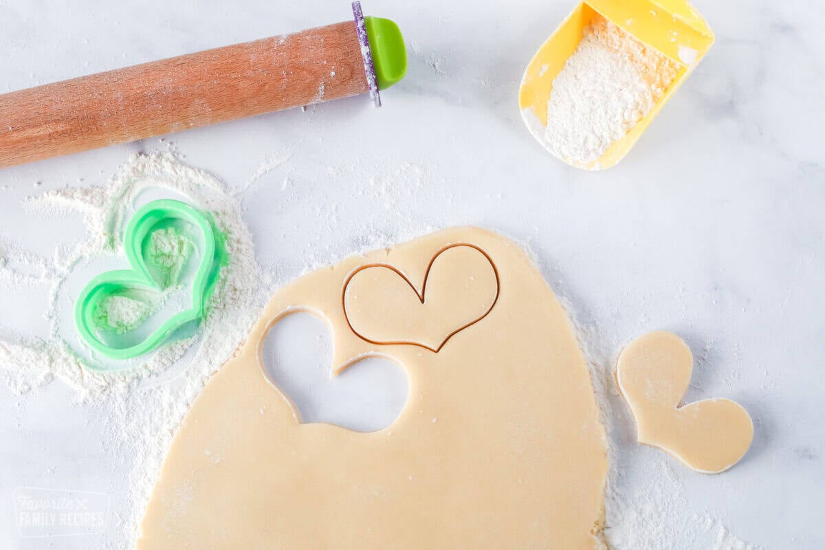 Sugar cookie dough with rolling pin and cut out heart shapes