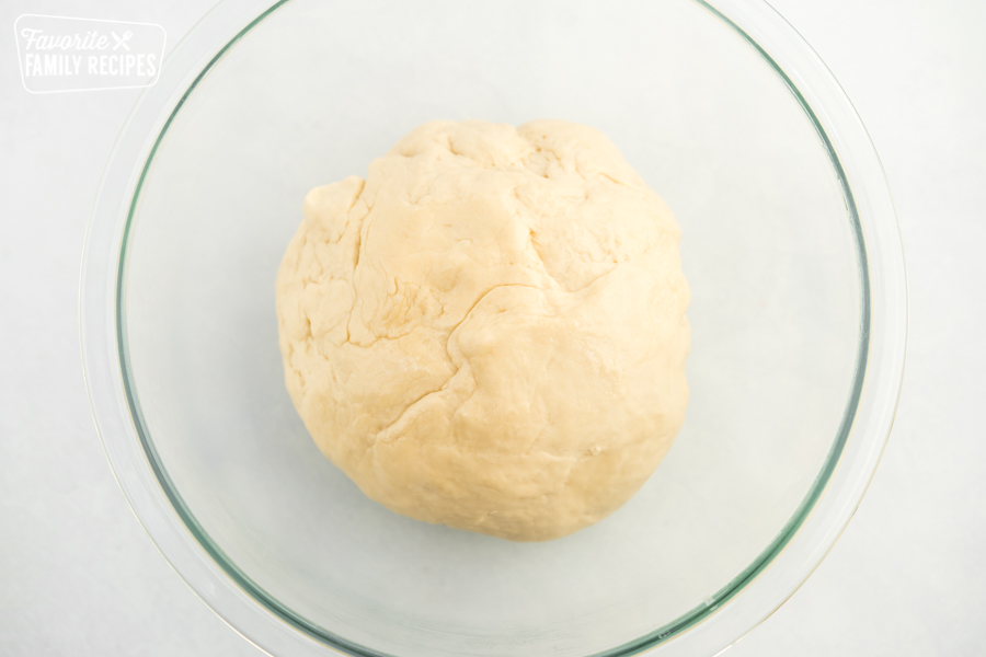 A ball of pizza dough in a glass bowl