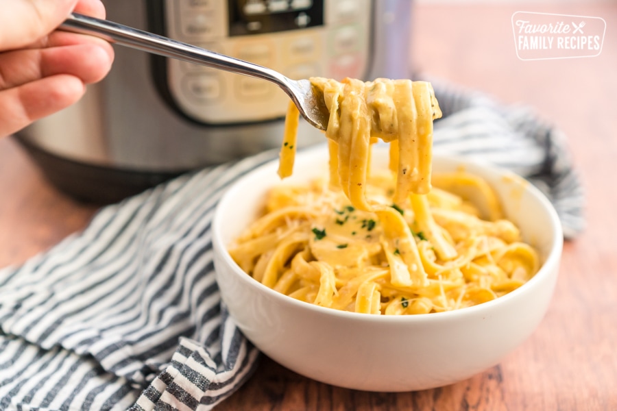 A bite of chicken alfredo on a fork.