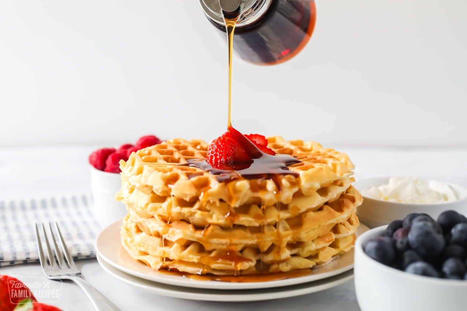 Syrup being poured onto homemade waffles.