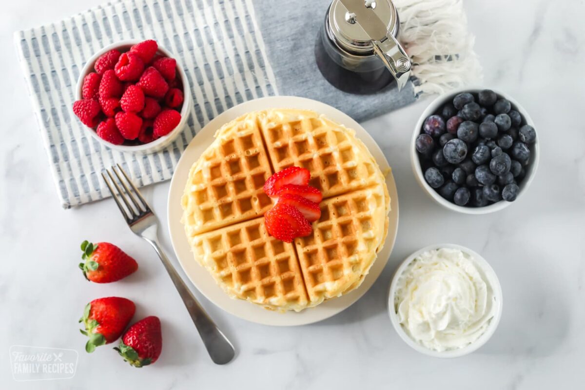 Waffles with syrup, strawberries, berries, and whipped cream