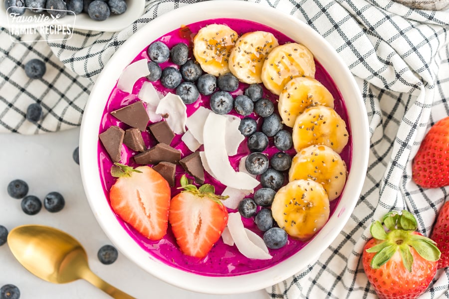 Acai bowl with bananas, coconut, blueberries, strawberries, and dark chocolate.