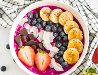 Acai bowl with bananas, coconut, blueberries, strawberries, and dark chocolate