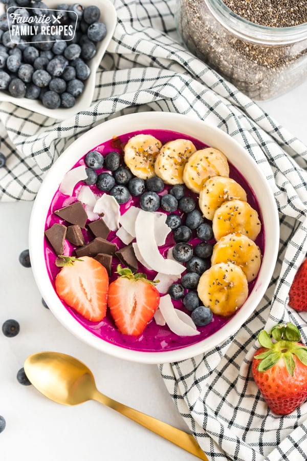 Acai bowl with bananas, coconut, blueberries, strawberries, and dark chocolate.