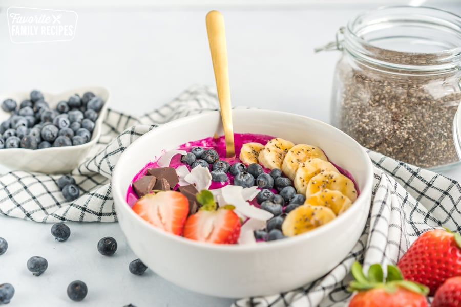 Smoothie bowl with bananas, coconut, blueberries, strawberries, and dark chocolate.