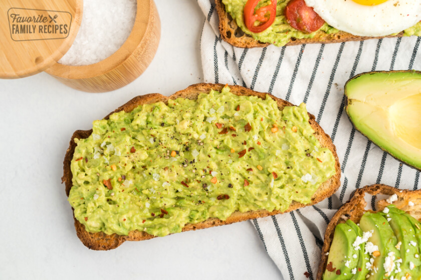 A piece of toast with mashed avocado, salt, pepper, and red pepper flakes