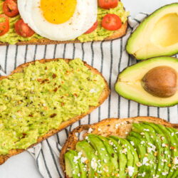Three pieces of toast, one with mashed avocado, salt, and pepper, one with sliced avocado, feta, and honey, and one with mashed avocado, tomato, and a fried egg