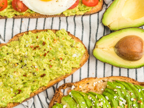 Three pieces of toast, one with mashed avocado, salt, and pepper, one with sliced avocado, feta, and honey, and one with mashed avocado, tomato, and a fried egg